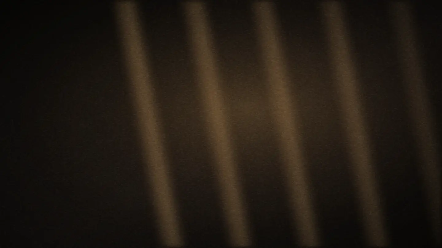 Low morning light falling through a shutter across a bare plastered wall.